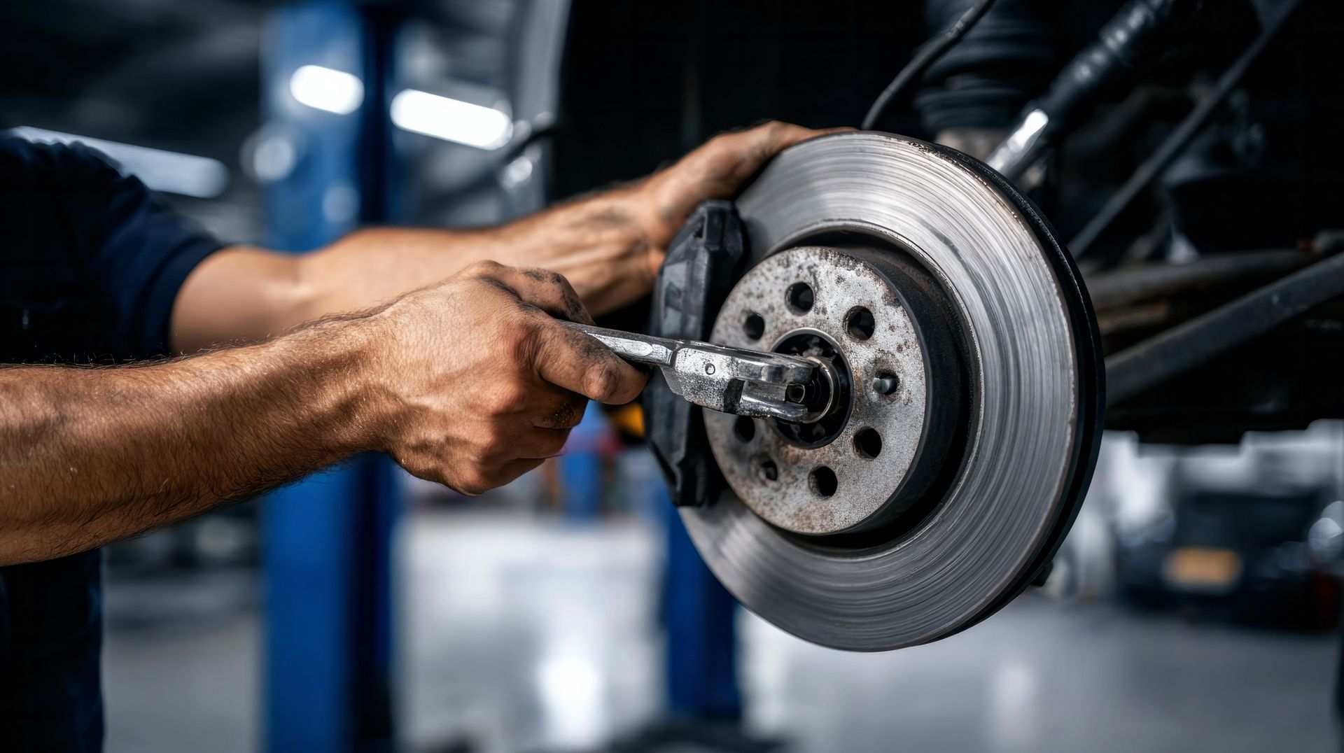 Dans un atelier de réparation, un mécanicien utilise un outil pour travailler sur le disque de frein d'une voiture.