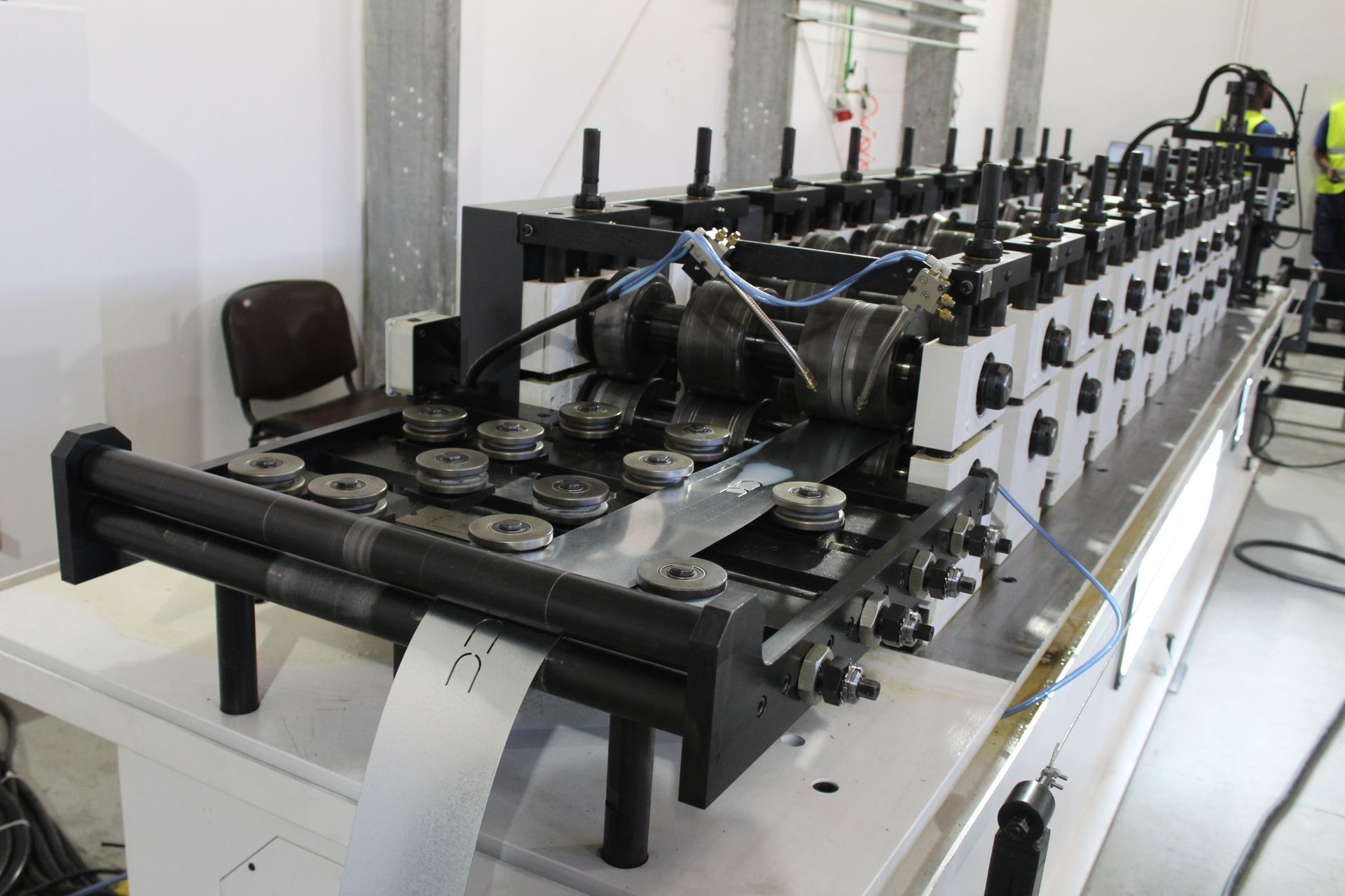 Máquina de conformação de rolos de chapas metálicas em ambiente de fábrica.