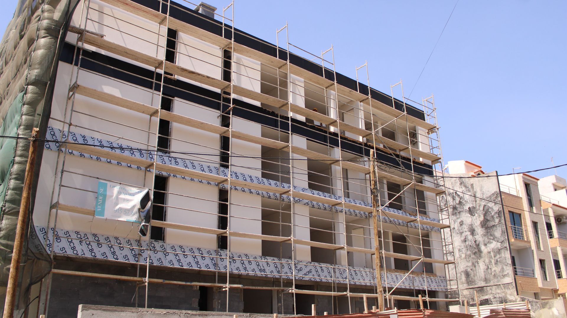 Prédio em construção com andaimes e paredes expostas.