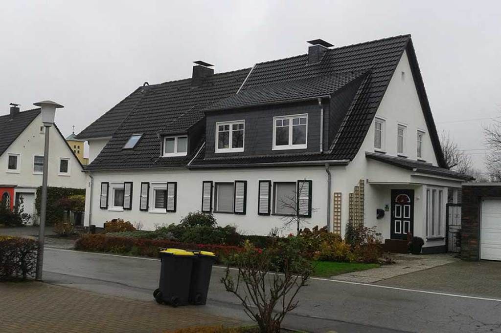 Weißer Fassadenanstrich eines Doppelhauses mit Fensterläden