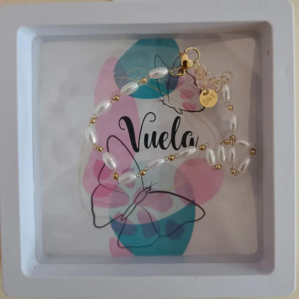 Letrero decorativo enmarcado con «Vuela», flores en tonos pastel y una mariposa con cuentas de perlas