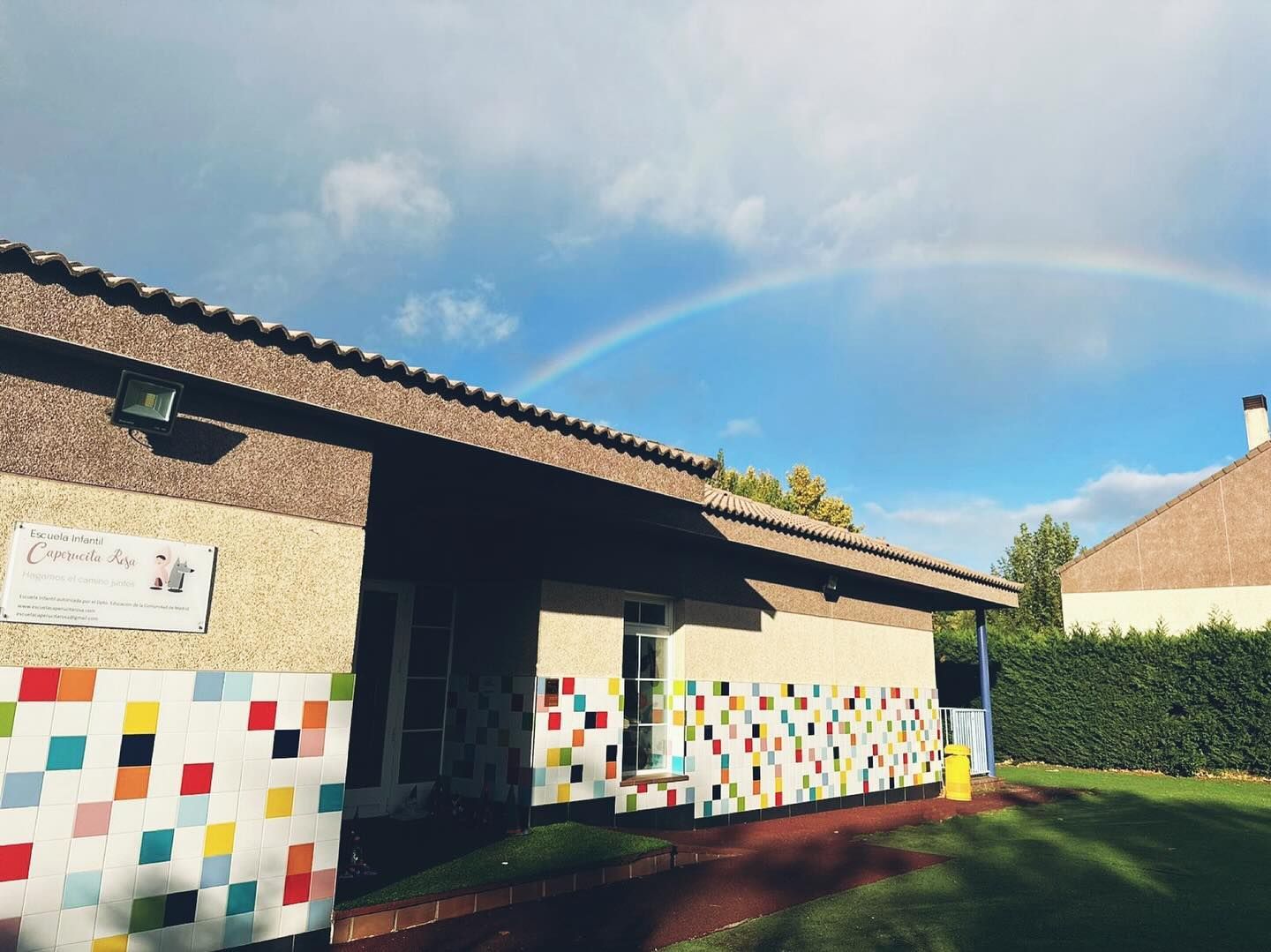Un edificio con azulejos de colores y un arco iris en el cielo.