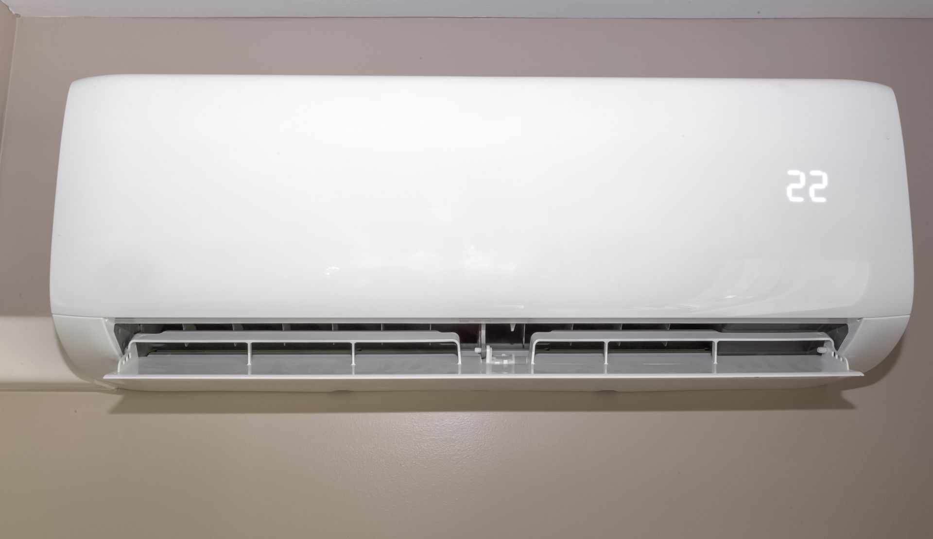 Climatiseur split blanc monté sur un mur beige, affichant le numéro 22.