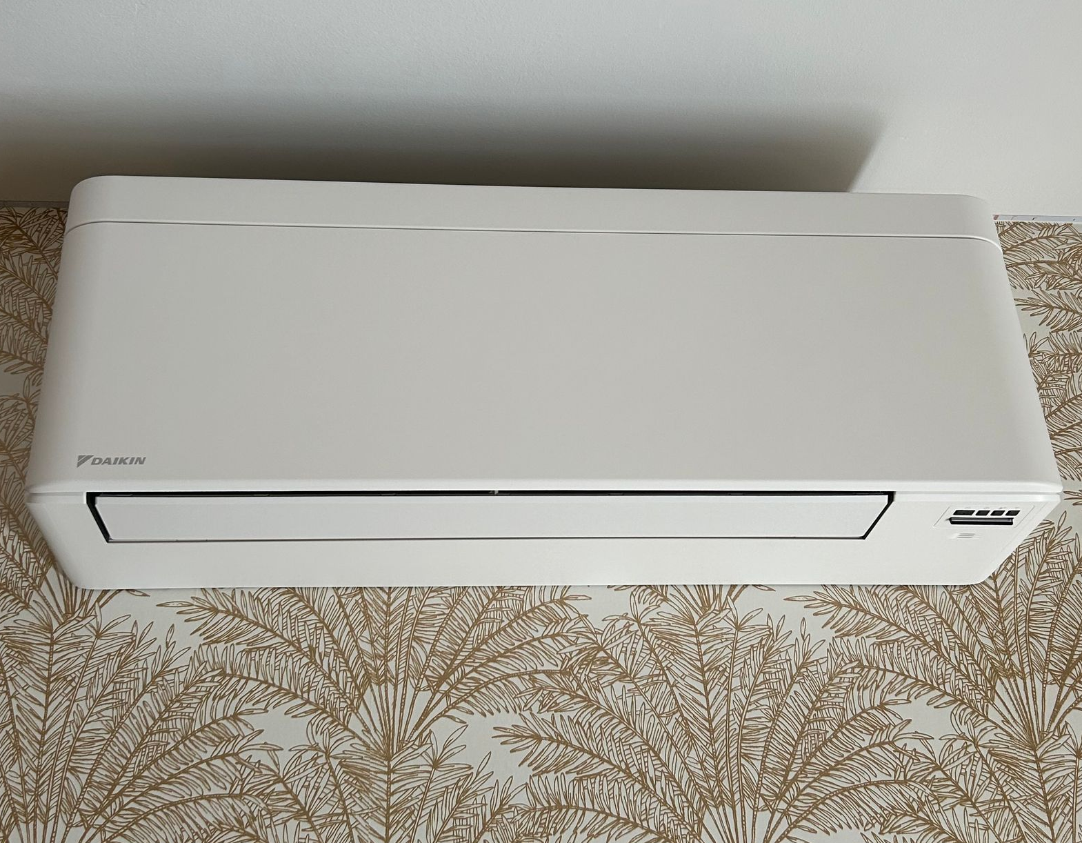 Climatiseur Daikin blanc sur papier peint à motifs.