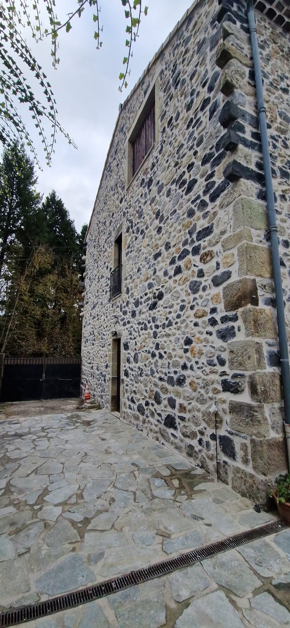 Tour et mur en pierre bordant un chemin pavé dans une ruelle étroite.