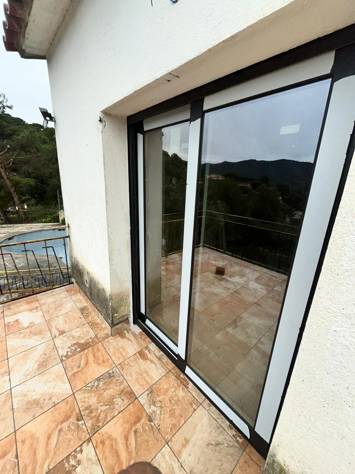 Puertas corredizas de cristal que dan a un balcón con baldosas y vistas panorámicas al exterior.
