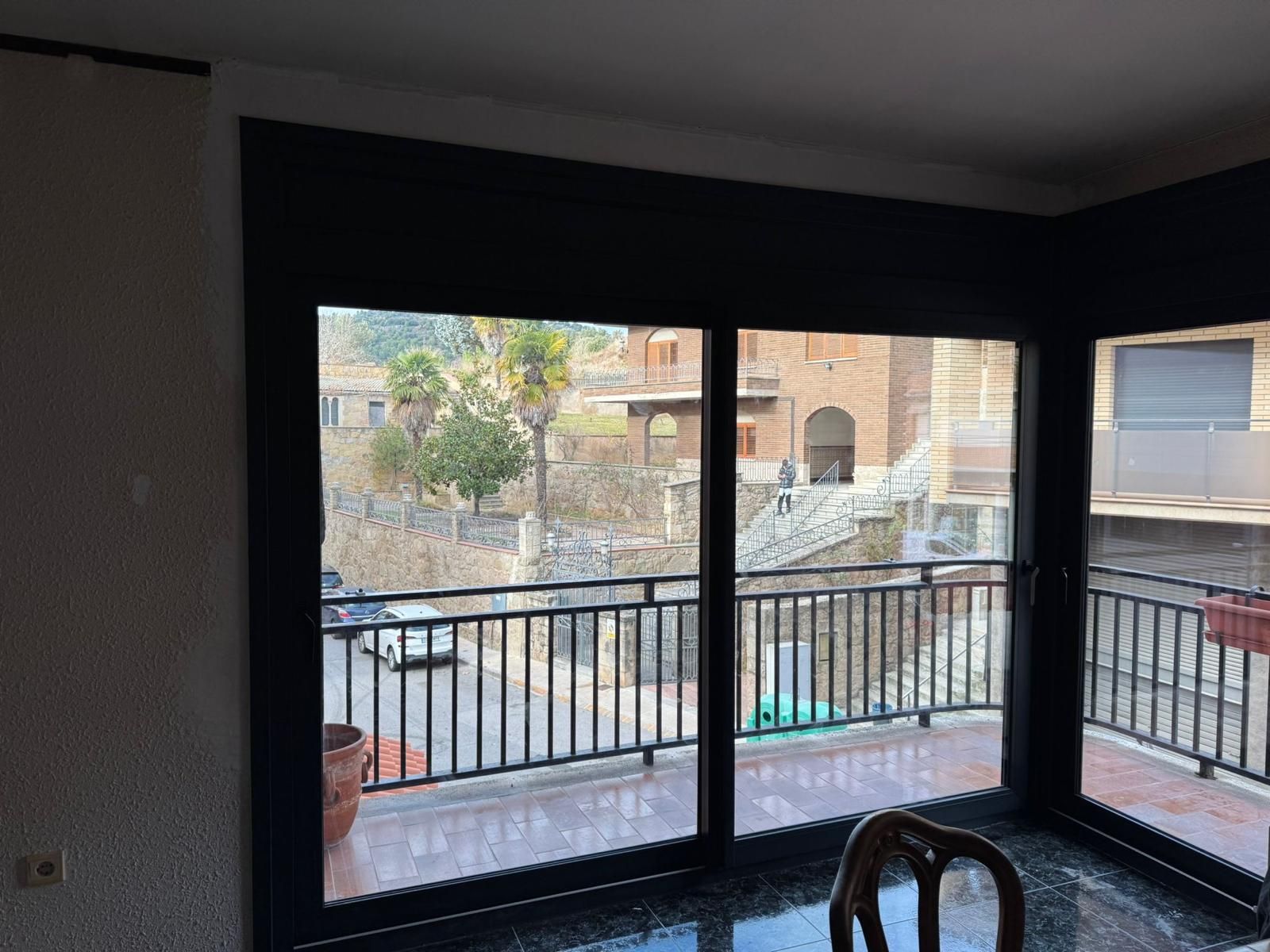 Puerta principal blanca con ventanas laterales, ubicada en la entrada de un edificio de piedra gris.