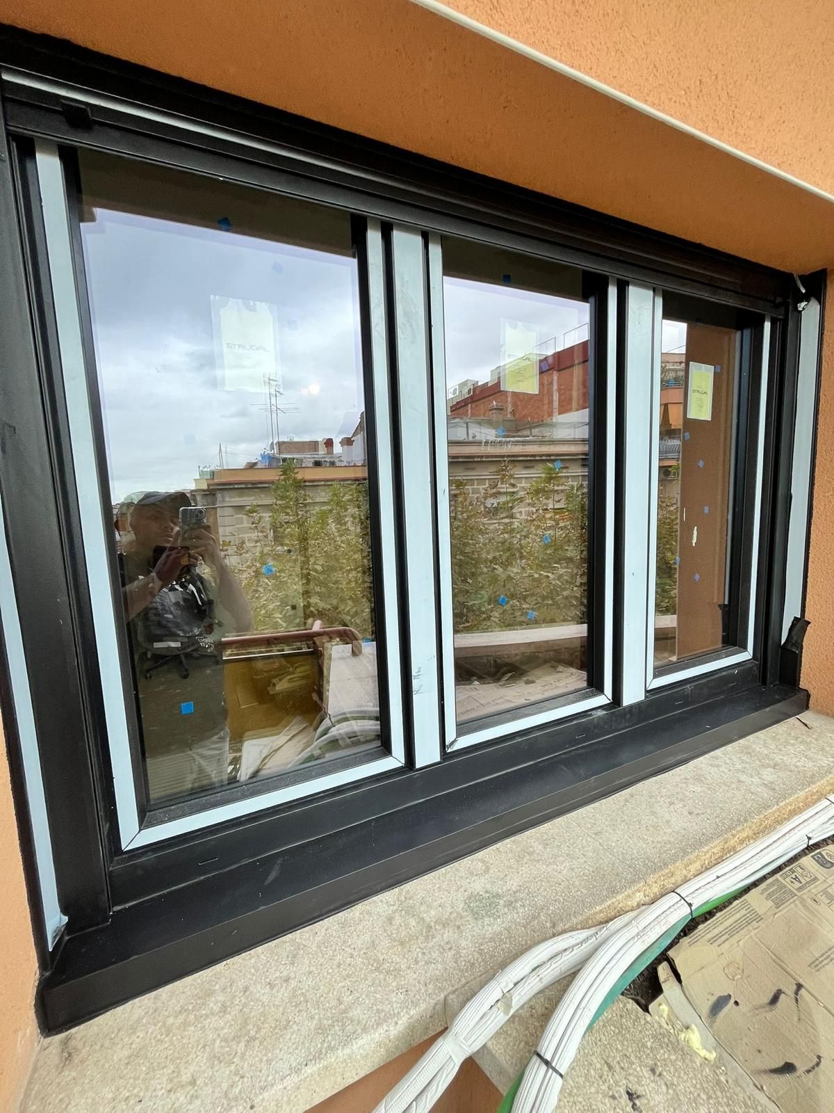 Unas puertas corredizas de cristal dan acceso a un patio soleado con macetas, mesas y sillas.