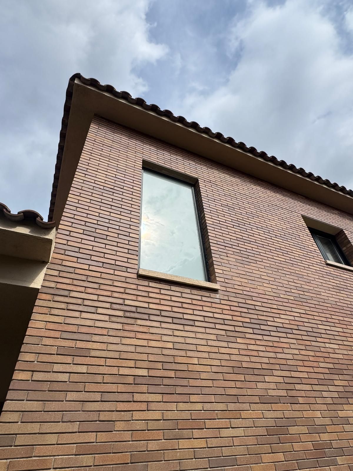 Habitación vacía con paredes blancas, suelo de madera y altas puertas francesas que dan a un balcón.