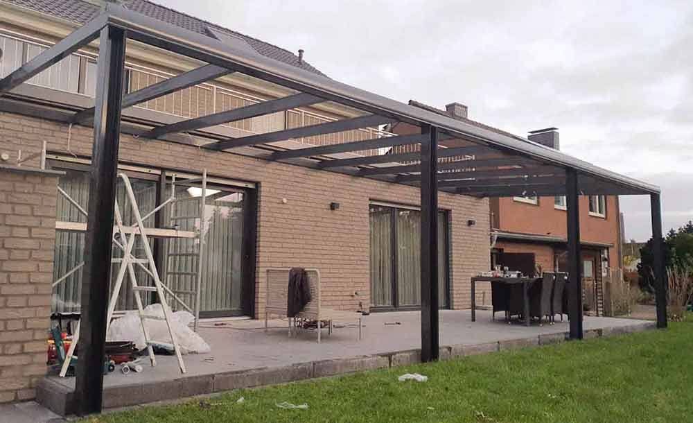 Ein Backsteinhaus mit Terrasse und davor liegender Pergola.