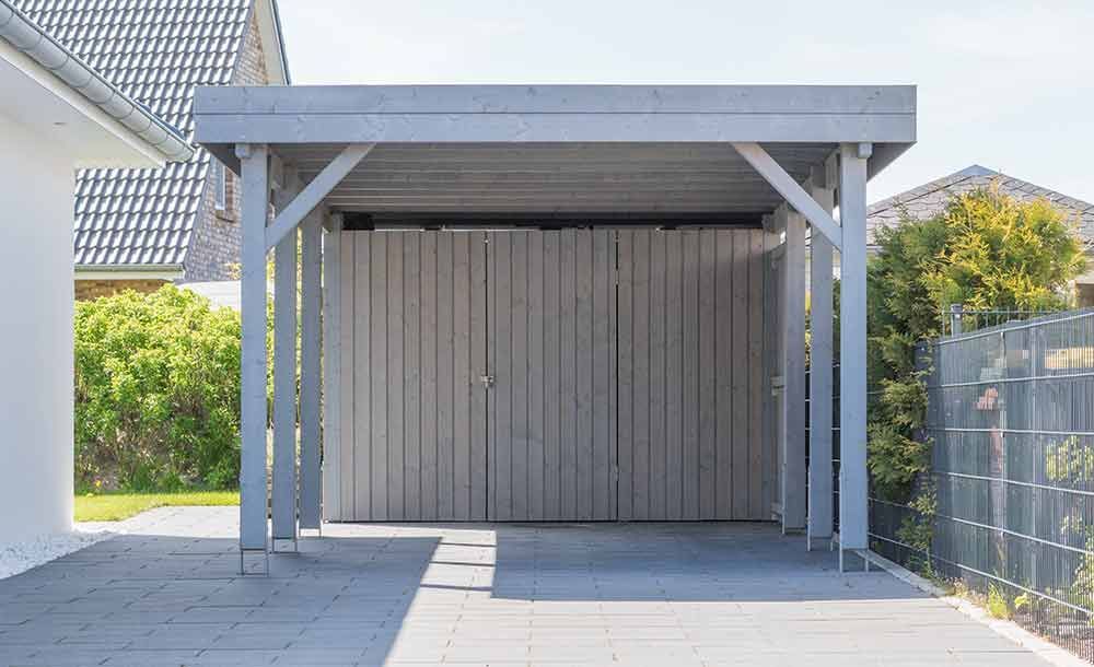 Ein Carport mit Garagentor im Hinterhof eines Hauses.