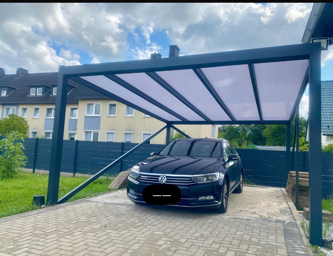Ein schwarzes Auto parkte unter einem schwarzen Carport mit weißem, durchscheinendem Dach.