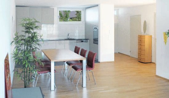Ein Esszimmer mit Tisch und Stühlen und einer Küche im Hintergrund.