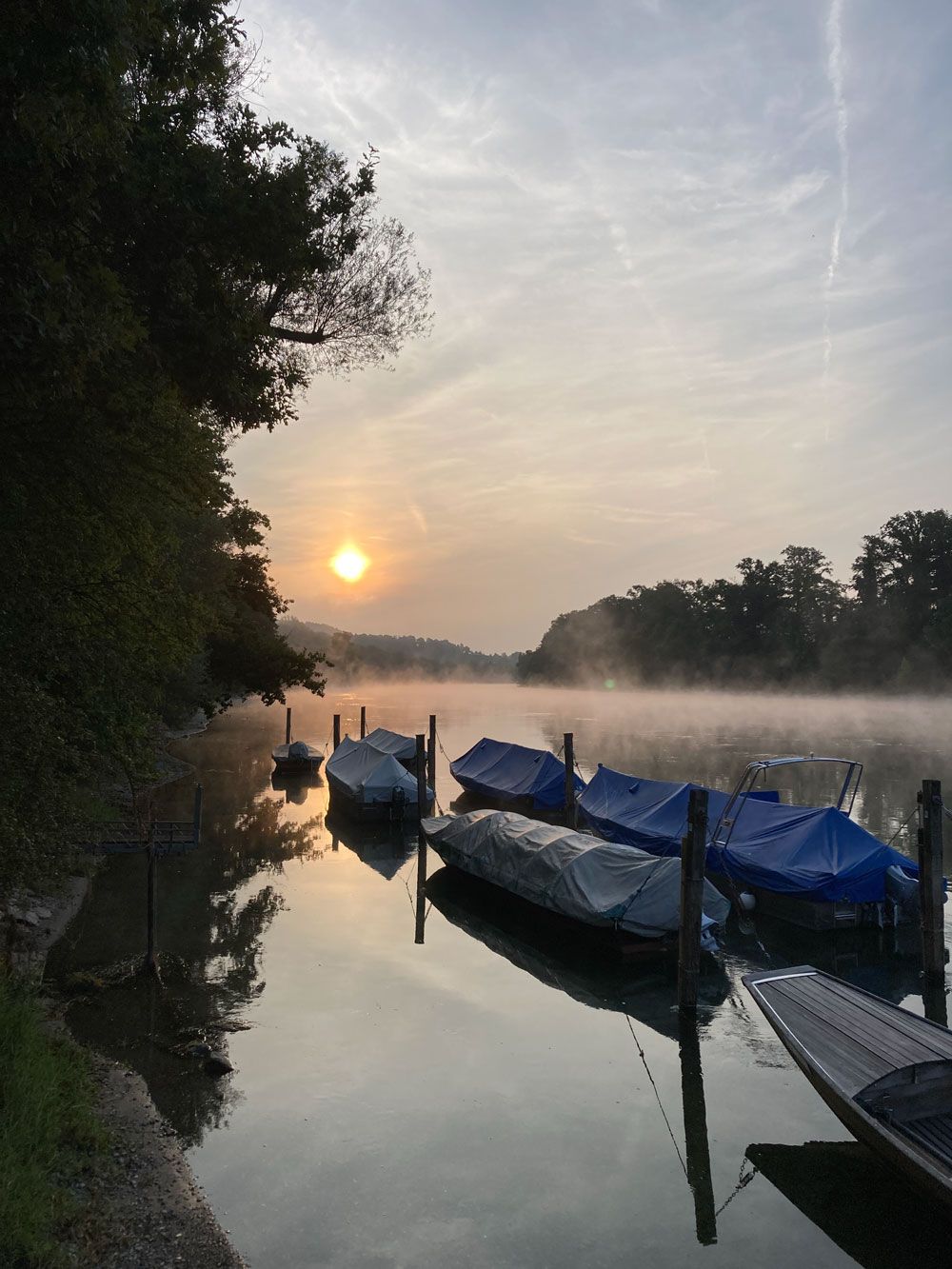 Eine Reihe von Booten liegt bei Sonnenuntergang an einem See vor Anker
