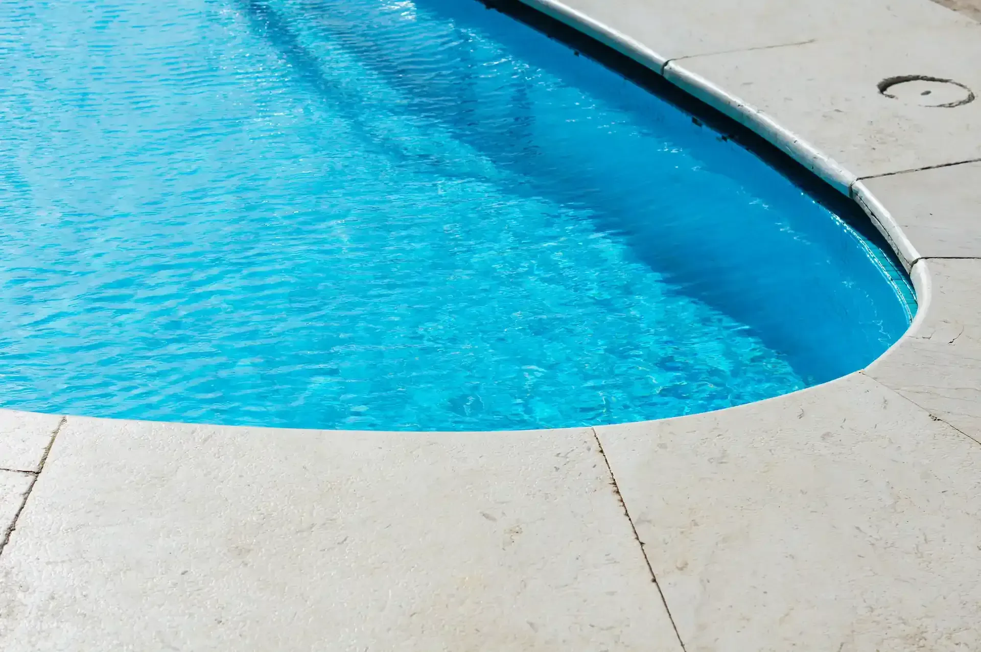 Piscina de color azul con borde de piedra de color claro.