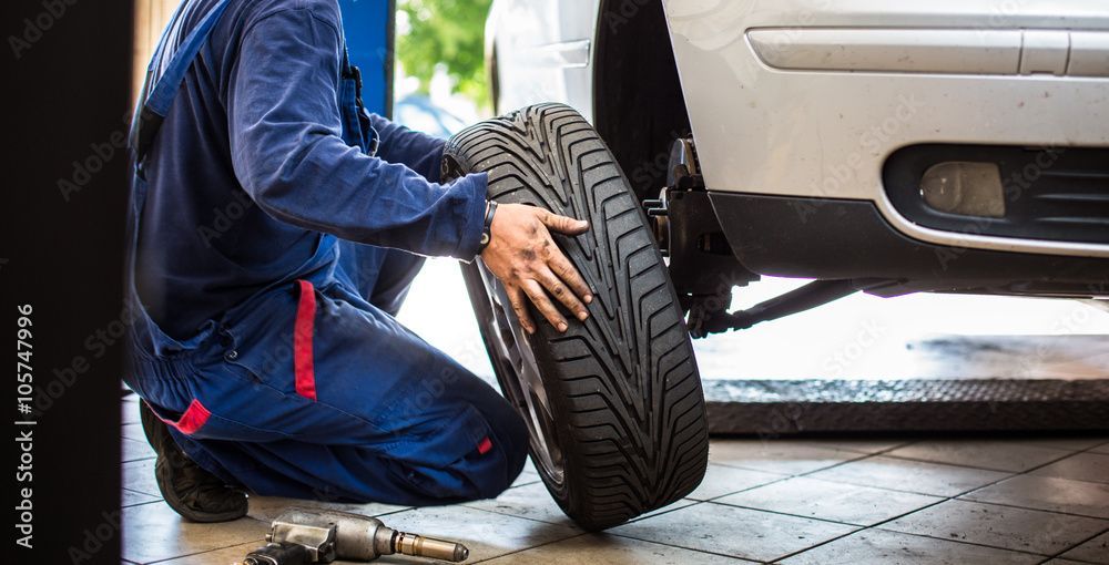 Ein Mechaniker wechselt in einer Garage einen Autoreifen.