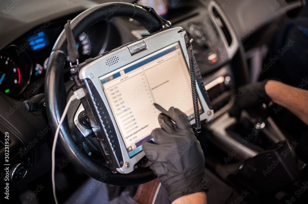 Ein Mechaniker benutzt ein Tablet in einem Auto.