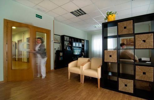 Una mujer camina por una habitación con sillas y un estante.