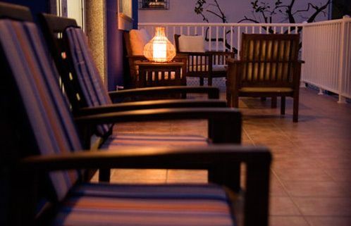 Una fila de sillas están alineadas en un balcón por la noche.