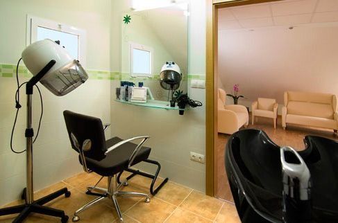 Una peluquería con silla, lavabo, espejo y secador.