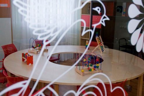 Una habitación con una mesa redonda y sillas y juguetes encima.