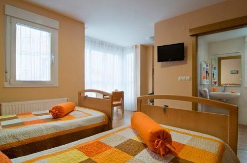 Un dormitorio con dos camas y un televisor en la pared.