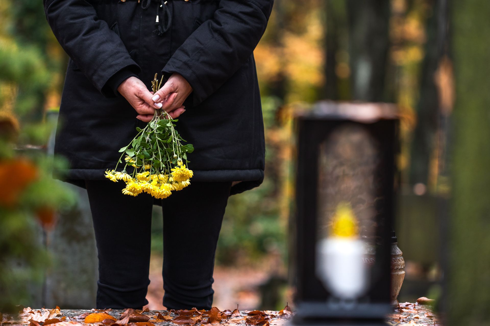 Homme en noir tenant un bouquet de fleurs jaunes