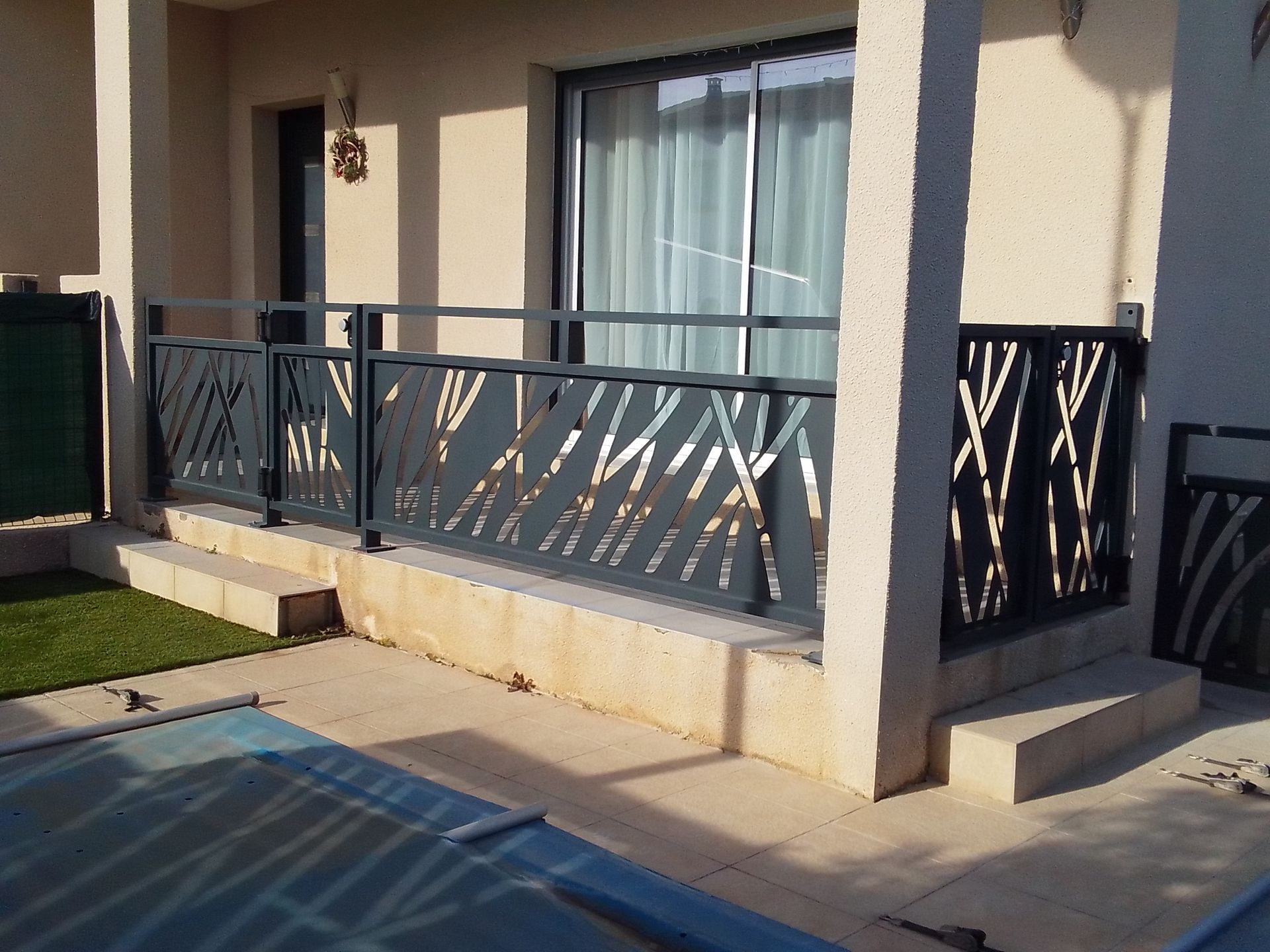 Garde-corps en métal gris au design unique, près d'une piscine et d'une maison.