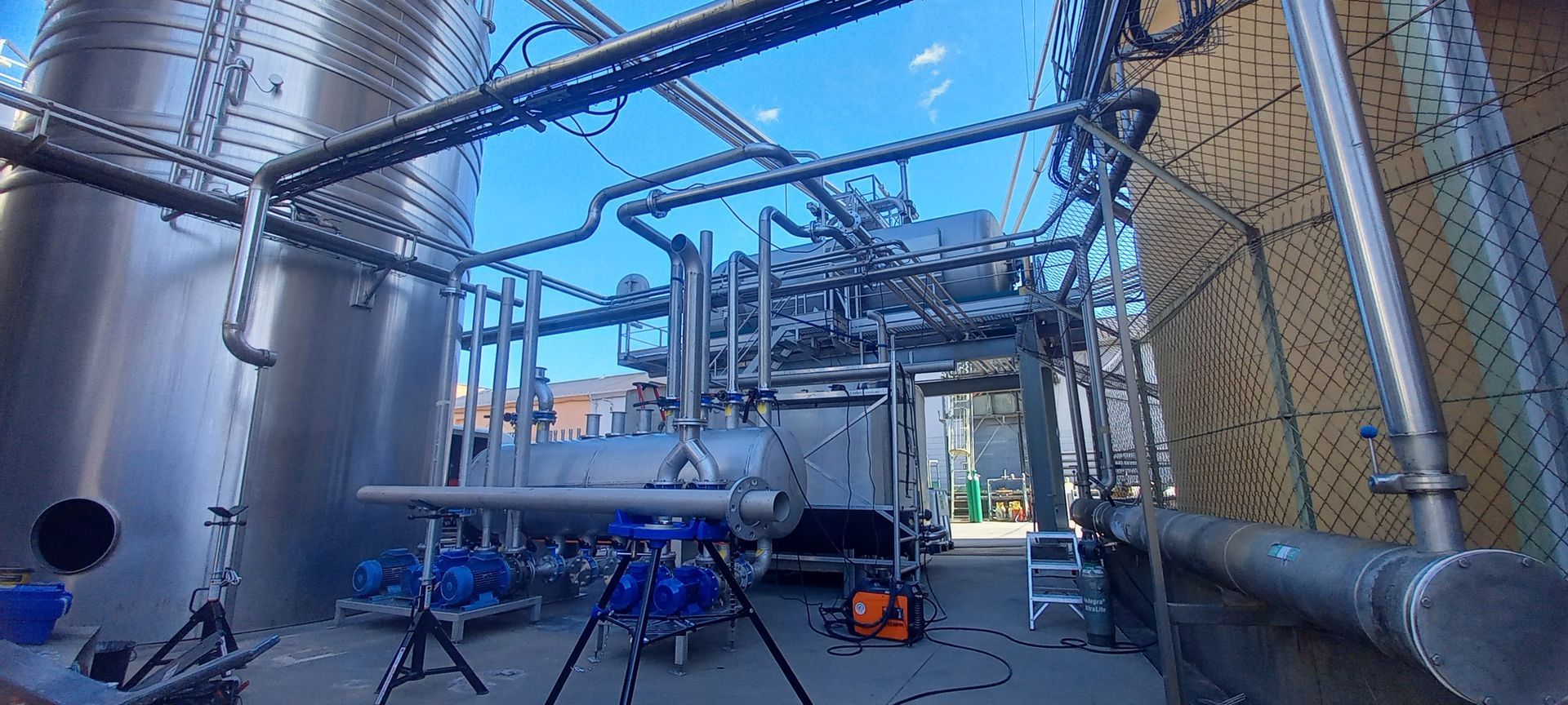 Machines industrielles et tuyaux contre un ciel clair.