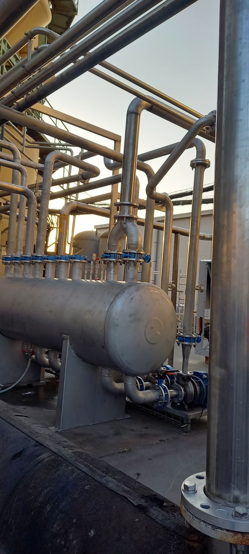 Tuyauteries et machines industrielles en extérieur. Des tuyaux en acier sont reliés à un grand réservoir.