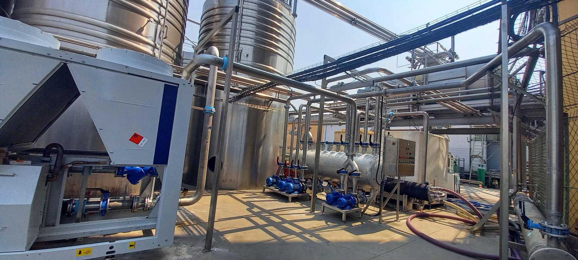 Installation industrielle avec réservoirs, tuyaux et machines en acier inoxydable.