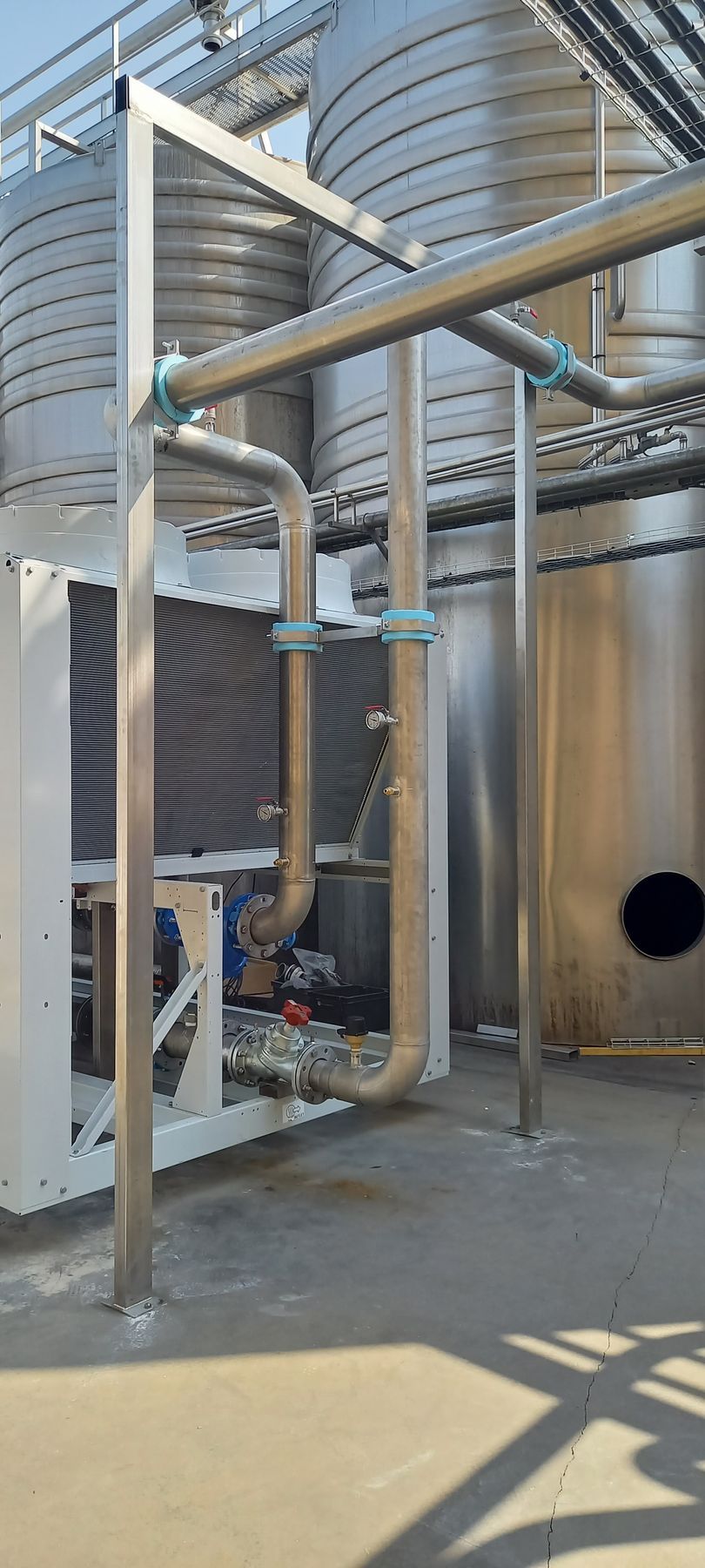 Équipement industriel avec réservoirs et tuyauteries métalliques sur un sol en béton.