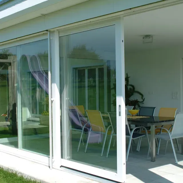 Las puertas corredizas de vidrio se abren a un patio con mesa y sillas.