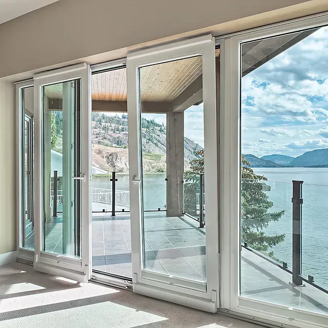 Una habitación con puertas corredizas de vidrio que conducen a un balcón con vista a un cuerpo de agua.