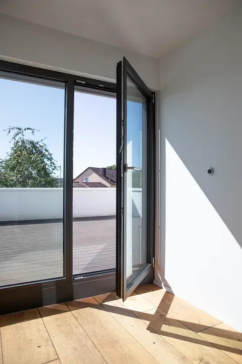 Una habitación vacía con una ventana grande y suelo de madera.