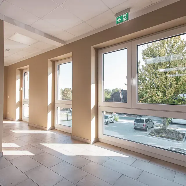 Una habitación con muchas ventanas y una señal de salida verde.