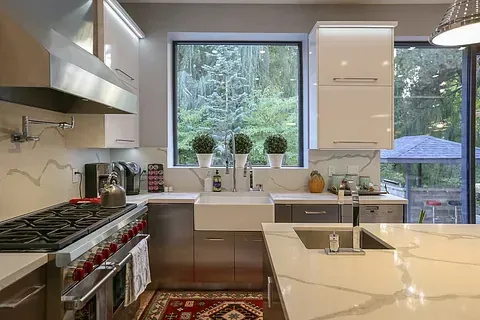 Una cocina con estufa, fregadero y ventana grande.
