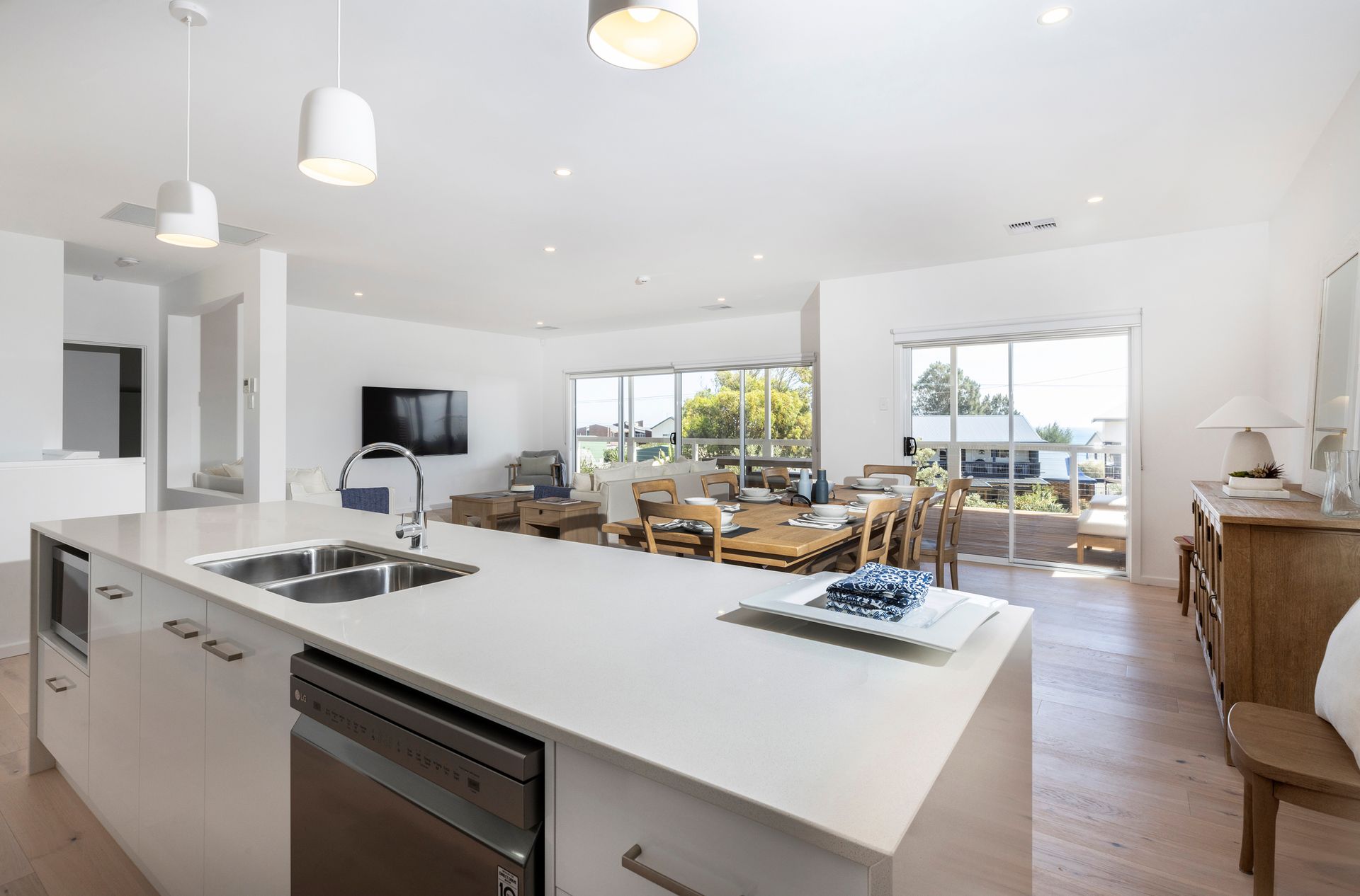 A large dining room with a wooden table and chairs and a flat-screen TV. Sellicks Beach, beach house, luxury accommodation