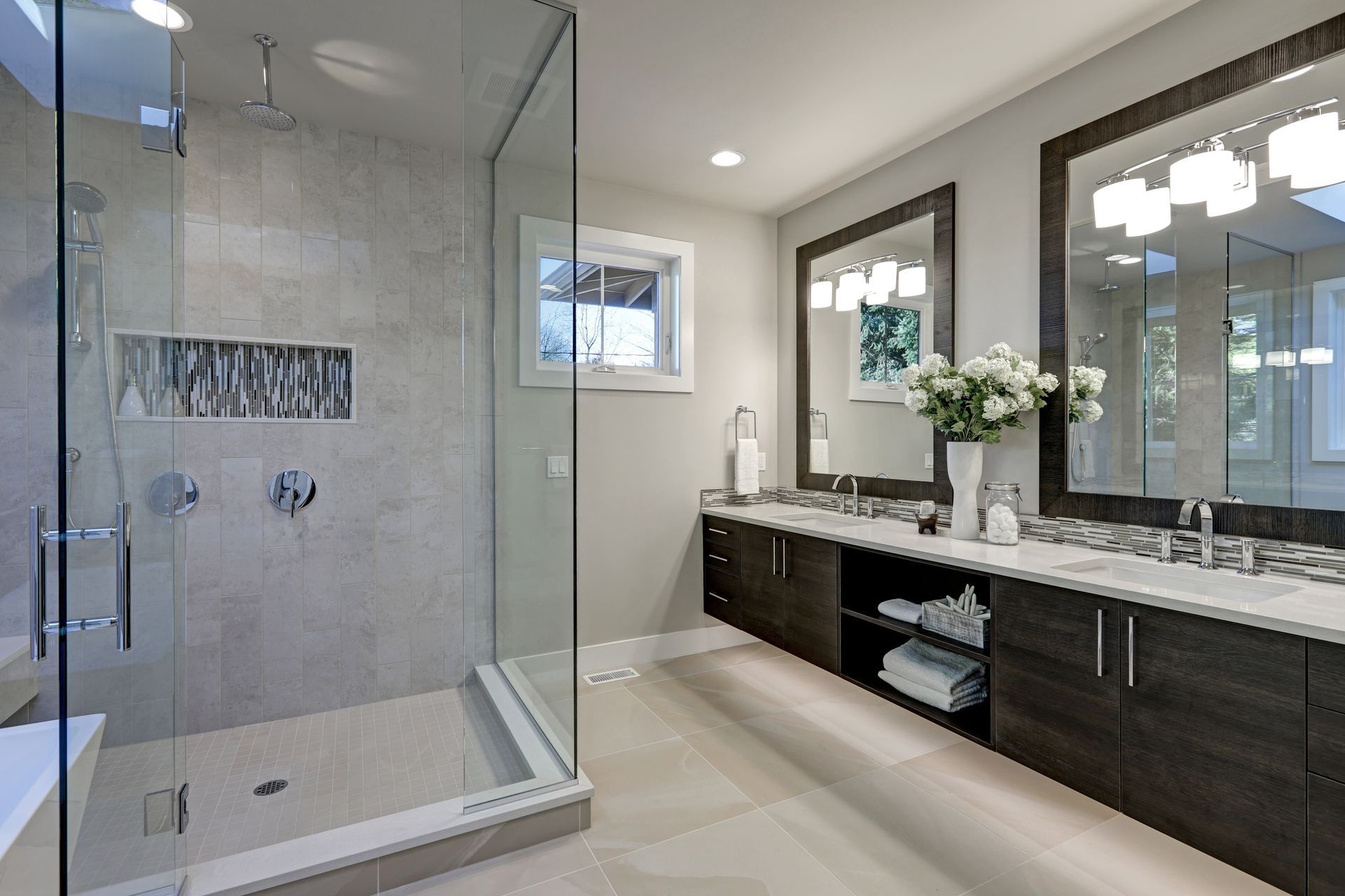 Salle de bains moderne avec douche à l'italienne en verre, meuble sous lavabo, double miroir et carrelage au sol neutre.