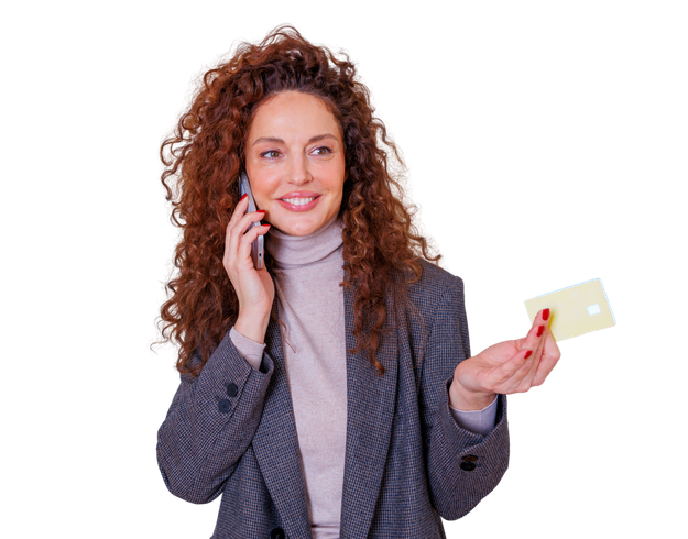 Une personne aux cheveux bouclés porte un blazer et un col roulé, et parle au téléphone tout en tenant une carte de crédit vierge.