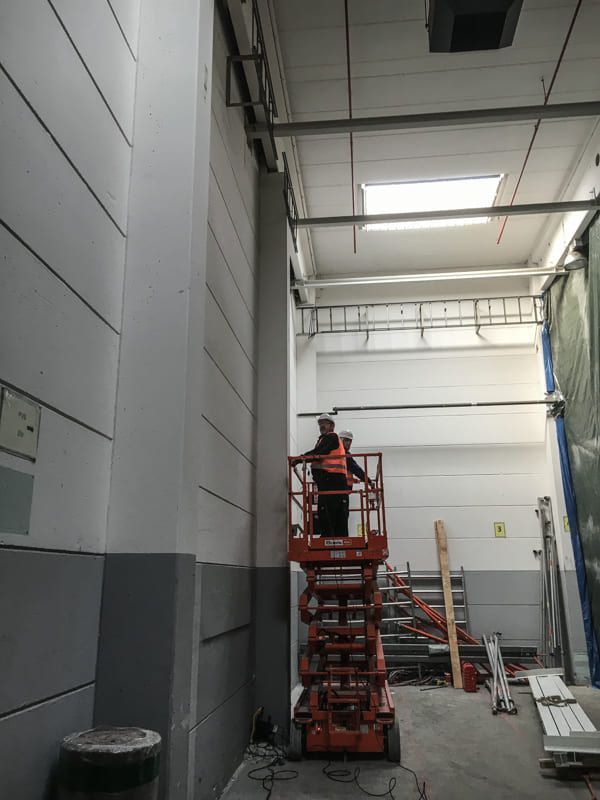 Ein Mann steht auf einer Scherenbühne in einer Lagerhalle.