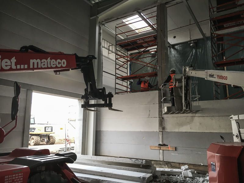 Mit einem Kran wird eine Wand in einem Gebäude entfernt.