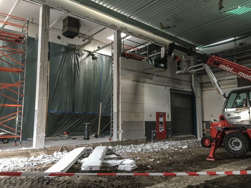 Mit einem Kran wird eine Wand in einem Gebäude entfernt.