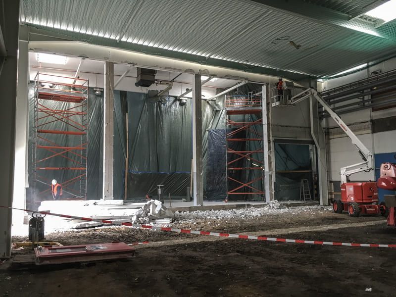 Mit Gerüst und Kran wird ein großes Gebäude errichtet.