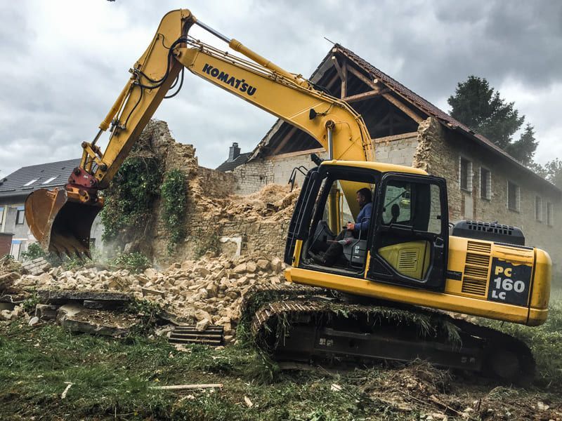 Ein gelber Komatsu-Bagger zerstört ein Haus.