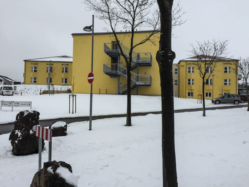 Eine verschneite Gegend mit einem gelben Gebäude im Hintergrund