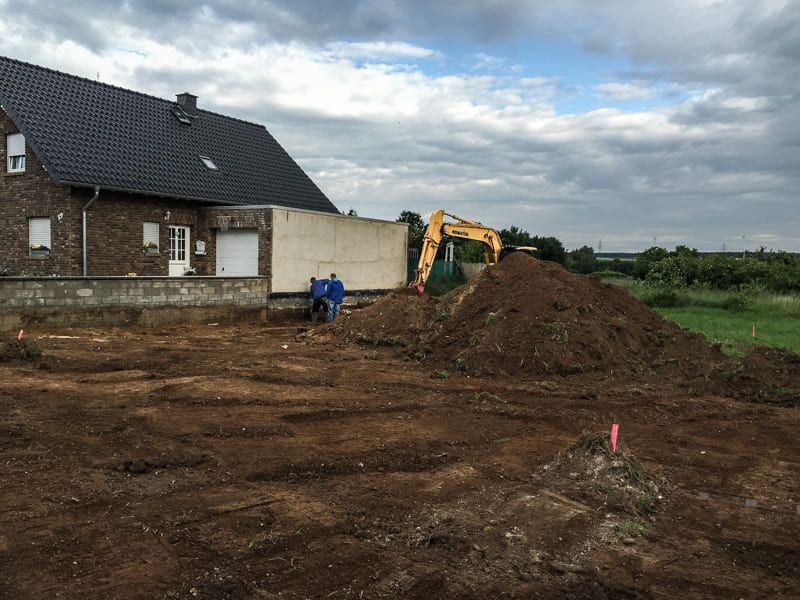 Vor einem Haus liegt ein großer Erdhaufen.