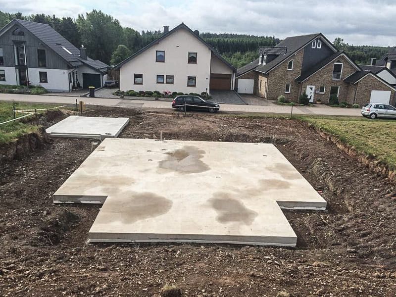 Ein Auto steht im Dreck vor einem Haus