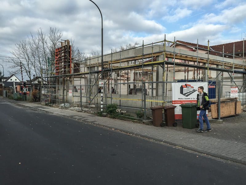 Ein Mann geht vor einem im Bau befindlichen Gebäude die Straße entlang.