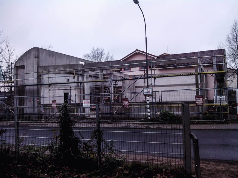 Ein Zaun umgibt ein im Bau befindliches Gebäude